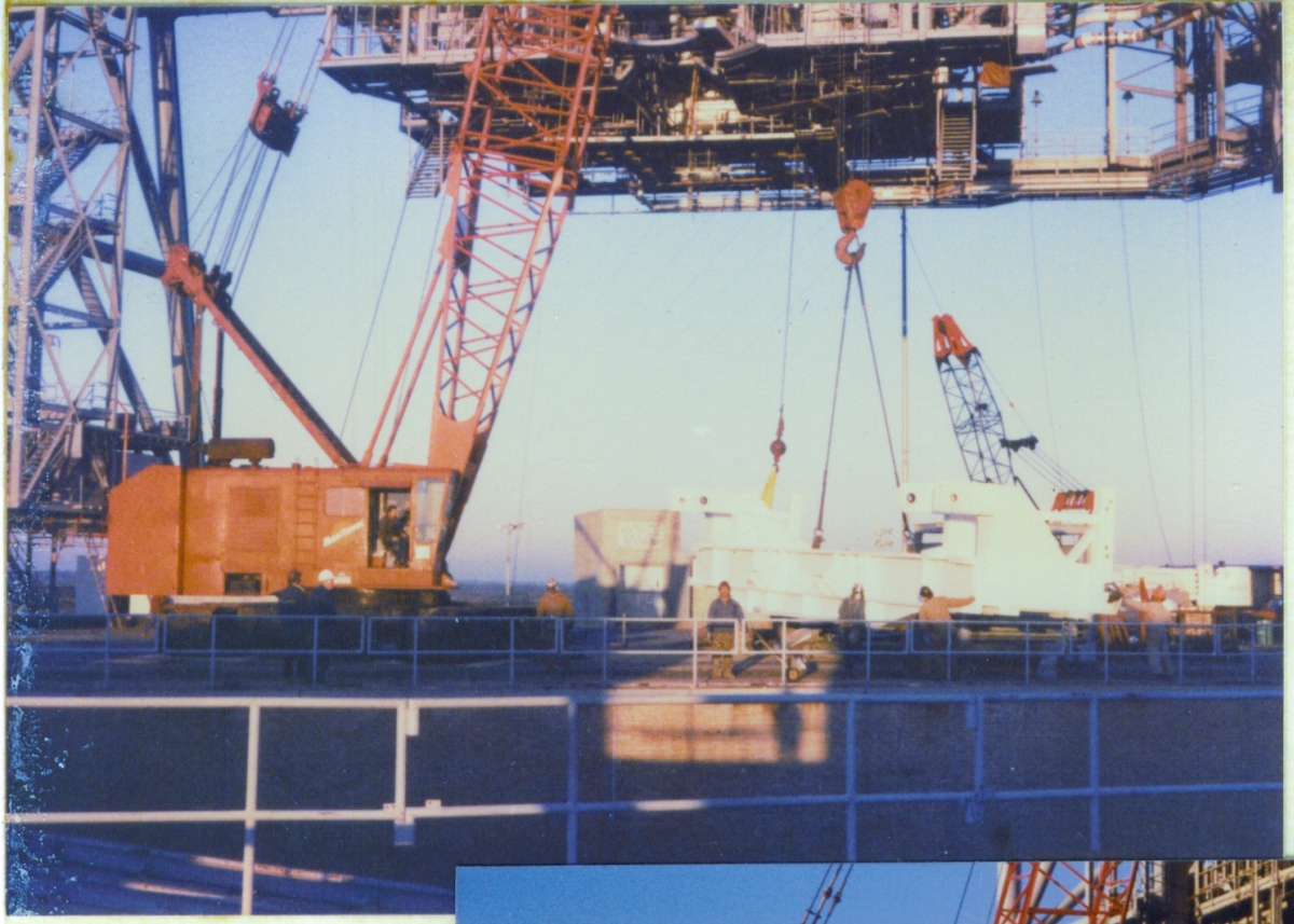 Union ironworkers from Local 808, working for Ivey Steel Erectors, begin a long difficult day, lifting the PGHM Bridge Beam off the ground, and into its final position just beneath the roof framing of the Payload Changeout Room at Launch Complex 39-B, Kennedy Space Center, Florida. In this image, the Bridge Beam has just broken contact with the ground and is being swung around into its proper orientation, prior to being tilted with the crane's jib line, in a way that will allow it to fit (just barely) through the opening in the front of the PCR.